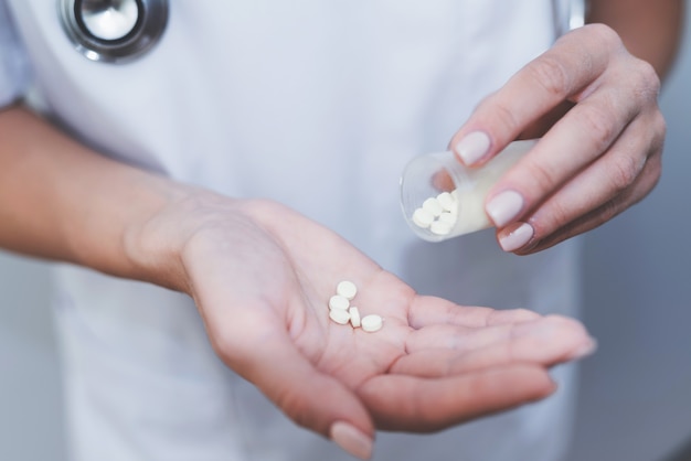 Close up. A nurse is holding various pills in her hands.