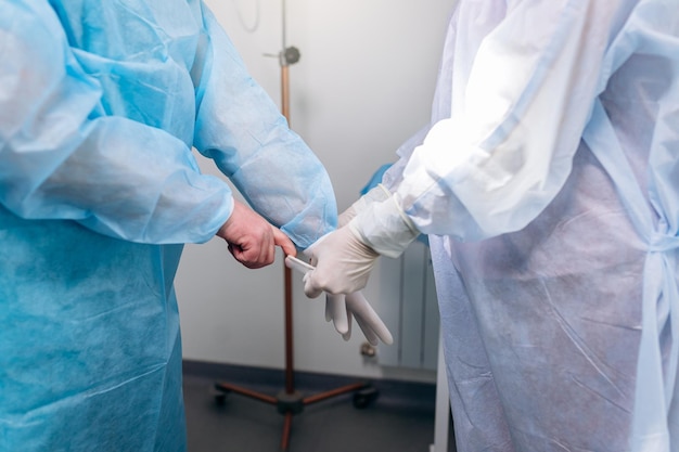 Close up of nurse putting on medical gloves on surgeon before the operation Doctors prepare for surgery in the operating room put on a medical uniform