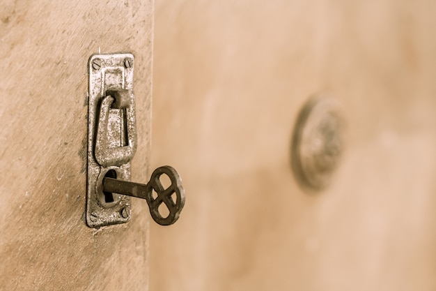 Close up old door with old lock and key. Old rusty key inside a keyhole. Selective focus on key