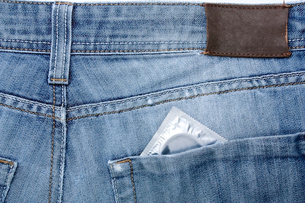 Close-up old jeans and a condom in his back pocket, symbol of safe sex