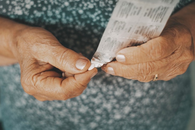 Close up of old woman hands taking pills medicine Health and unhealthy mature elderly people using pharmacy treatment to prevent bad condition diseases Concept of aged people taking care with pills