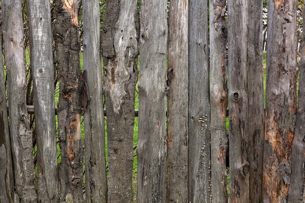 Close-up of an old wooden fence with a birdhouse in the village of a summer day