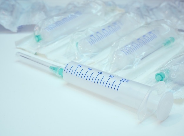 Close-up of one syringe with attached needle and pack of syringes