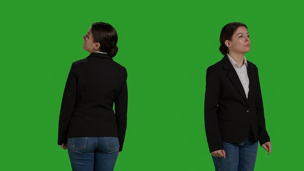 Close up of optimistic businesswoman in suit standing over greenscreen backdrop, waiting in studio. Corporate employee looking stylish and acting confident on camera, company worker.