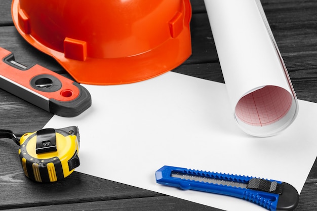 Close up orange hardhat and variety of repair tools with copyspace in the middle over wooden  