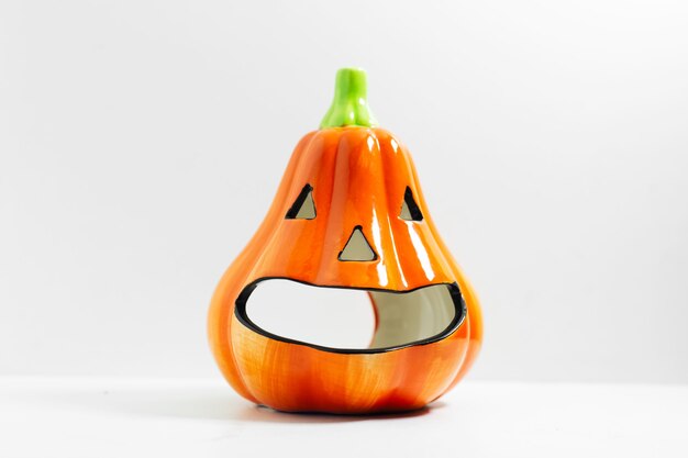 Close-up of orange small halloween pumpkin on white surface.