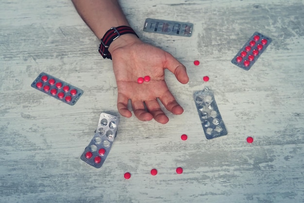 Photo close up of overdose pills and addict on the hands of men the man committing suicide by overdosing on medication red tablets in the hand of a young man