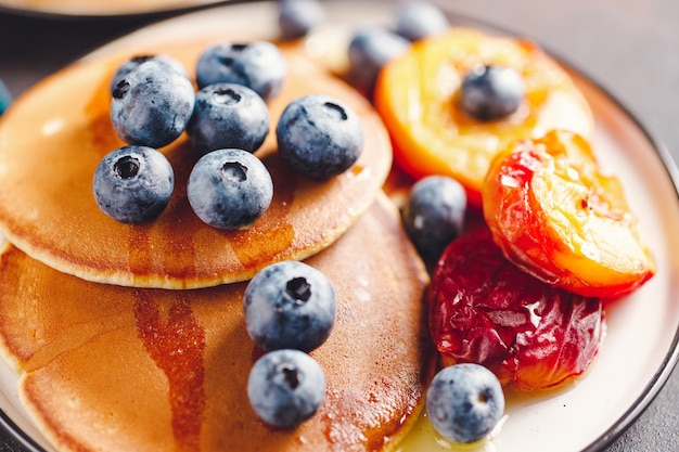 Close up of pancakes with grilled peaches fresh blueberry and maple syrup