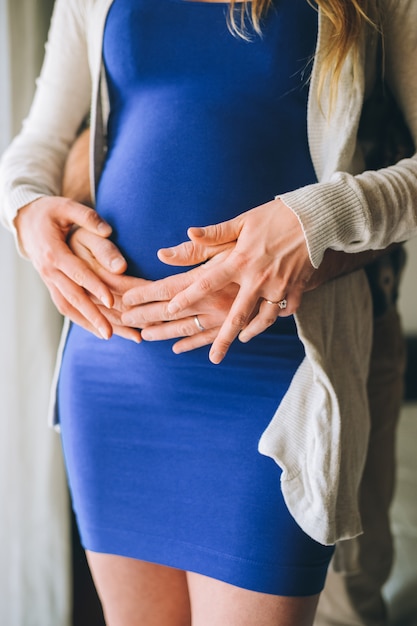 Close up of parents hands touching pregnant belly at home