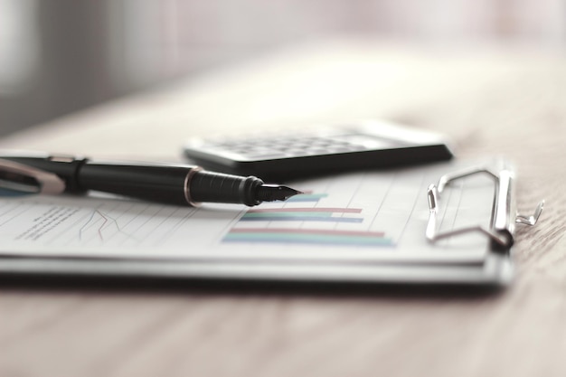 Close up pen calculator and clipboard on wooden table busines