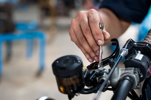 close up. People holding hand are repairing a motorcycle Use a wrench and a screwdriver 