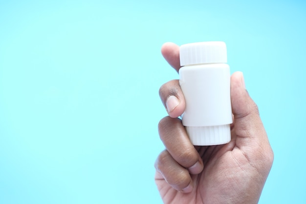 Close up of person hand holding pill container .