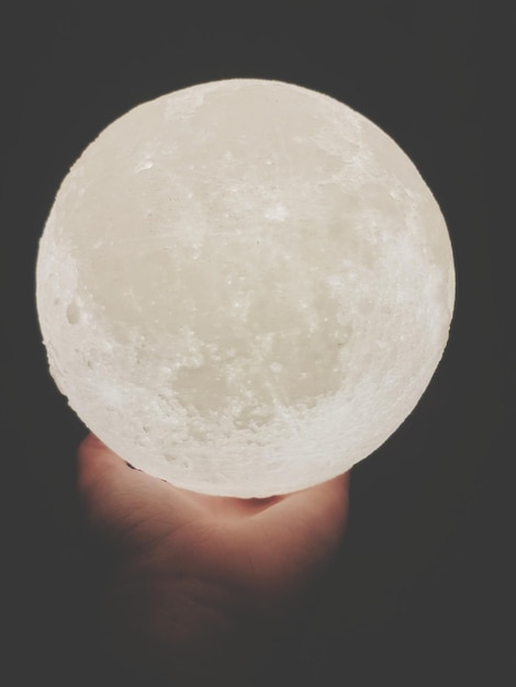 Close-up of person holding illuminated circle over black background