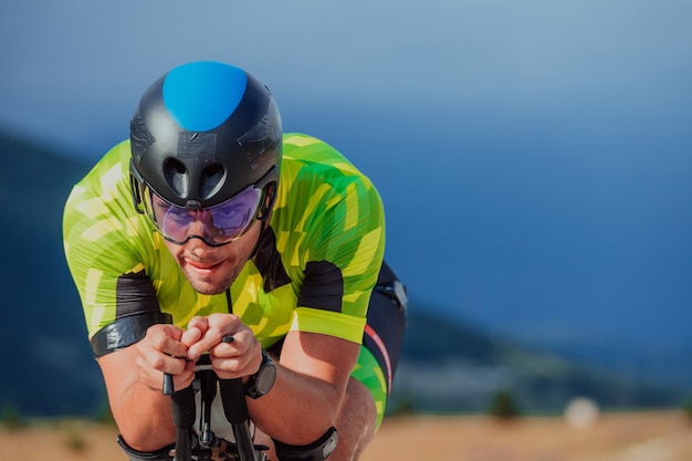 Close up photo of an active triathlete in sportswear and with a protective helmet riding a bicycle. Selective focus.