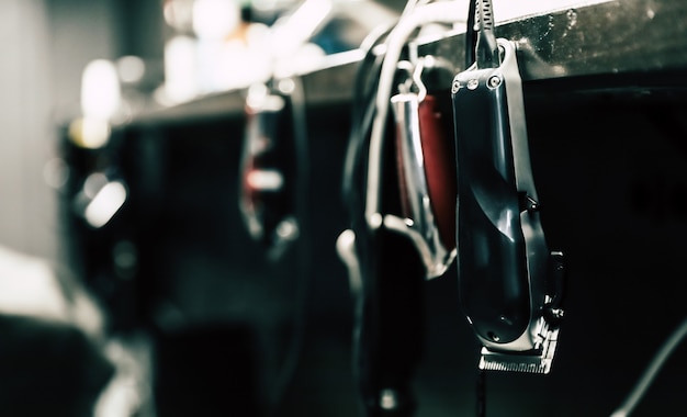 Close up photo of a barber toolkit of a wooden brush, trimmers, and scissors, lying on a barbershop counter.