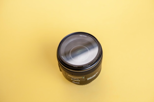 Close-up of a photo of a camera lens on a yellow background.