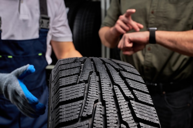 Close-up photo of car tire, focus on black tire, customer examining the surface and its characteristics before making purchase