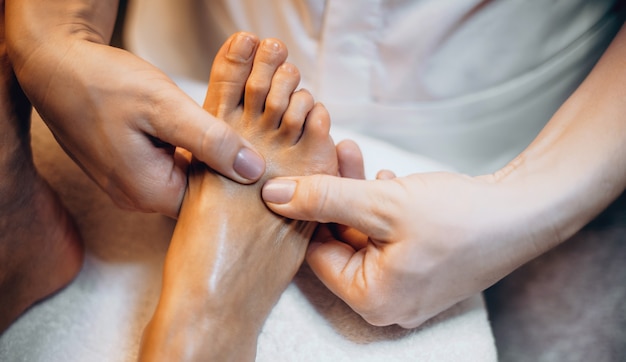 Close up photo of a caucasian masseuse having a feet massage session with a spa client