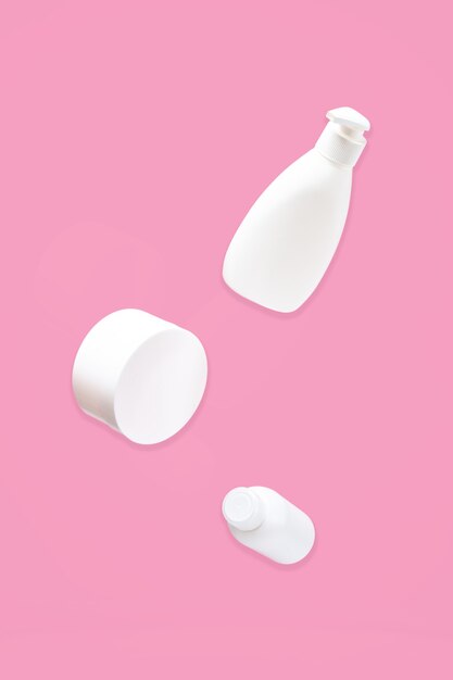 Close up photo of cosmetic bottle, jar with cream,  and dispenser on pink surface