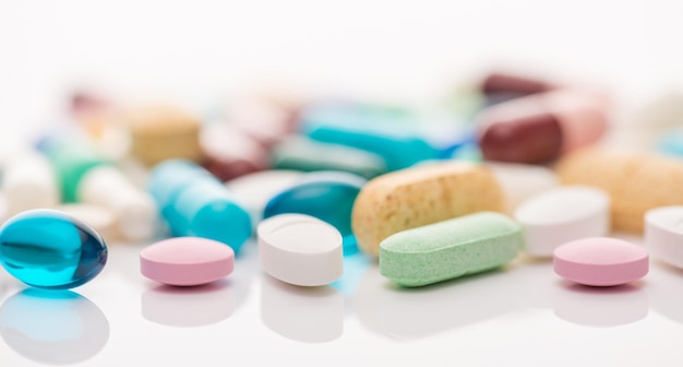 Close up photo of different shape multicolored pills lying on white color table