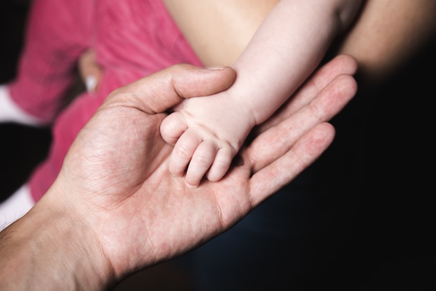 Close up photo of father holding baby hand