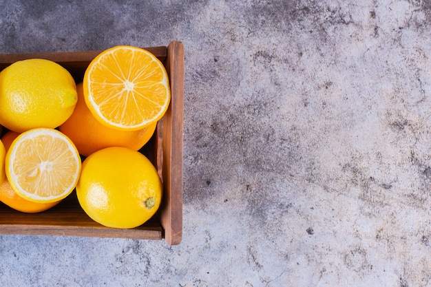 Close up photo of fresh juicy lemons in wooden box .