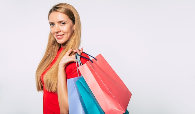 Close up photo of happy young blonde girl after visit of mall. Shopping concept. Woman with shopping bags