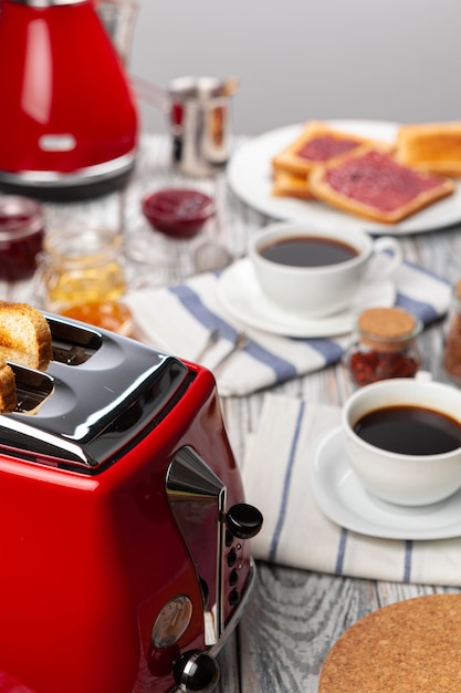 Close up photo of kitchen table with .appliances, kitchenware with toasts and jams