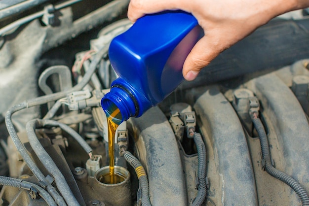 Close up photo of a male hand fill a car engine by oil