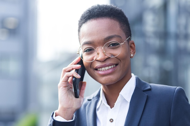 Close-up photo portrait of a young business woman, African American woman talking on the phone, smiling happy and happy, near the office outside