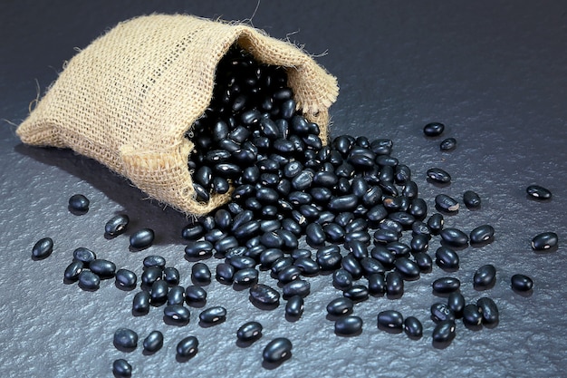 Close-up photo uncooked Vigna mungo or Black gram in sack on black table . Foods and dessert 