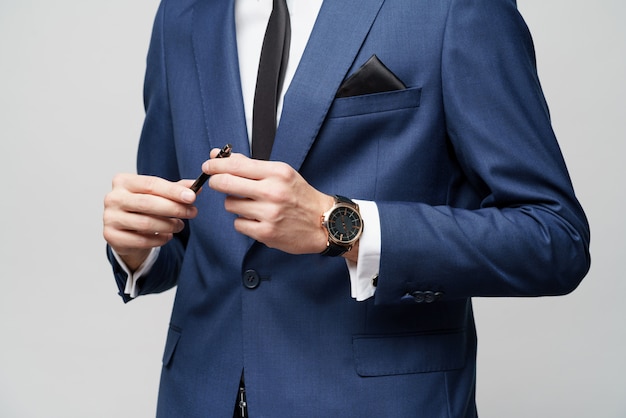 Close-up photo of young businessman wearing suit holding pen