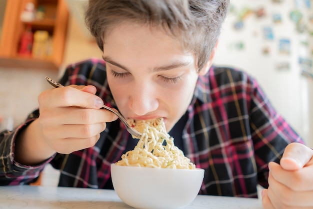 Close up photo of young man eating spaghetti from the bowl