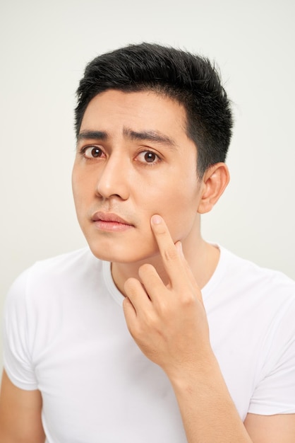 Close up photo of young man looking for acnes on his face