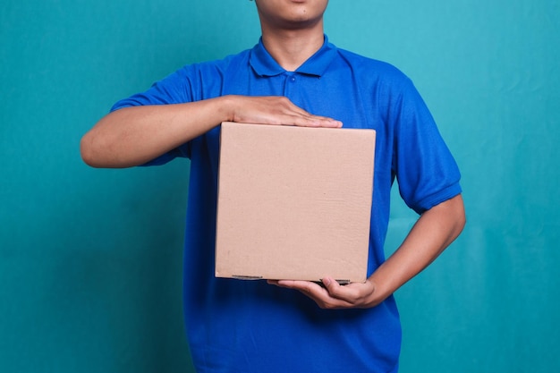 Close up picture of delivery man in blue uniform work as dealer courier hold a blank cardboard box