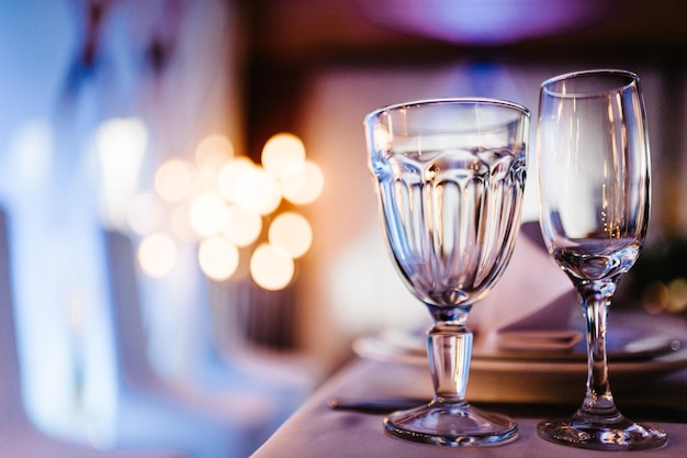 Close up picture of empty glasses in restaurant and cutlery Silverware or flatware on plates glasses for champagne and wine glasses Reflection bokeh and bright light