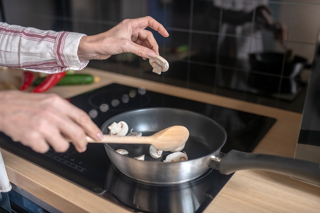 Close up picture of a woman stirring food on a frying pan