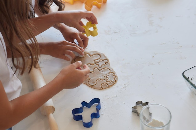 Close up picture of a young child's hand pressing a heart shape cookie cutter into soft rolled out dough to make sugar cookies