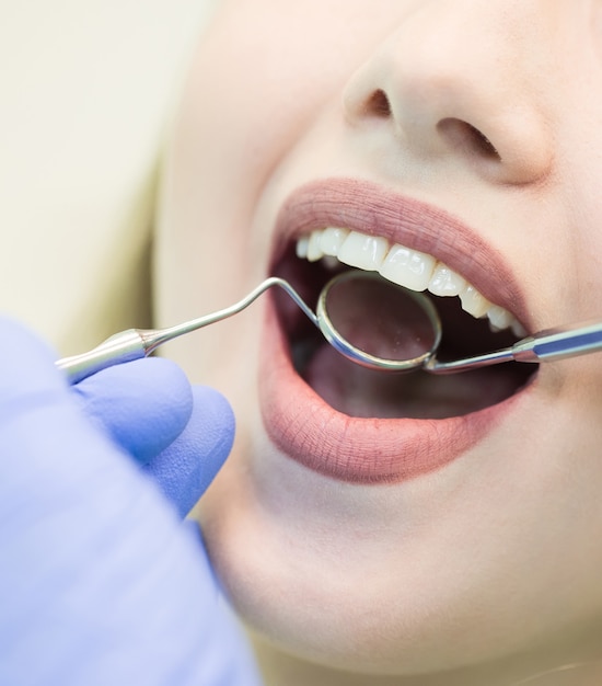 Close-up picture of young woman sitting in the dentist's chair with opened mouth at dentist's office while having examination.