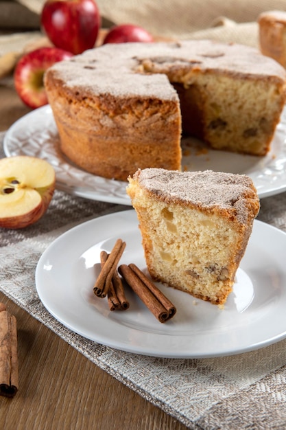 Photo close up piece of sponge cake or chiffon cake with apples so soft and delicious sliced with ingredients cinnamon eggs flour apples on wooden table home bakery concept for background and wallpaper