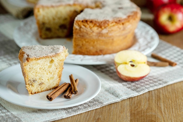 Photo close up piece of sponge cake or chiffon cake with apples so soft and delicious sliced with ingredients cinnamon eggs flour apples on wooden table home bakery concept for background