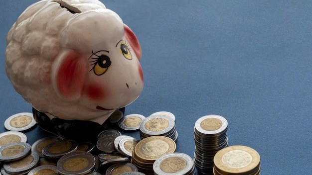 Close up of a piggy bank with coins on the side with copy space