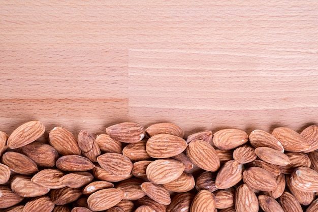 Close up pile of almonds on wooden floor,background.