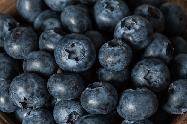 Close up pile of the blueberries in a brown ceramic bowl.