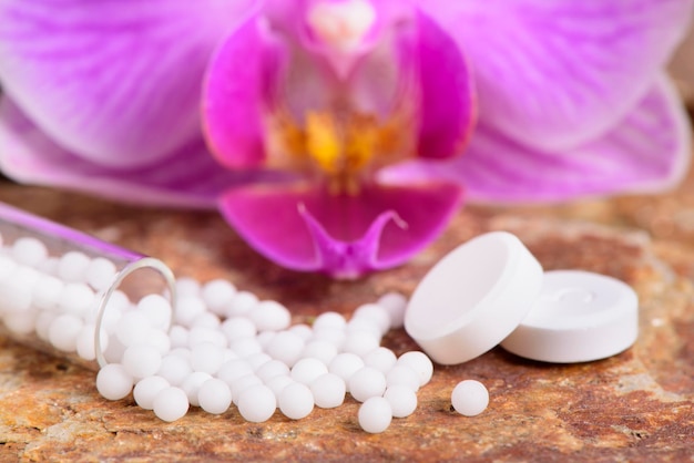 Close-up of pills with pink orchid on table