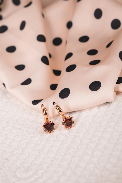 A close up of a pink and black polka dot dress with a gold diamond earring.