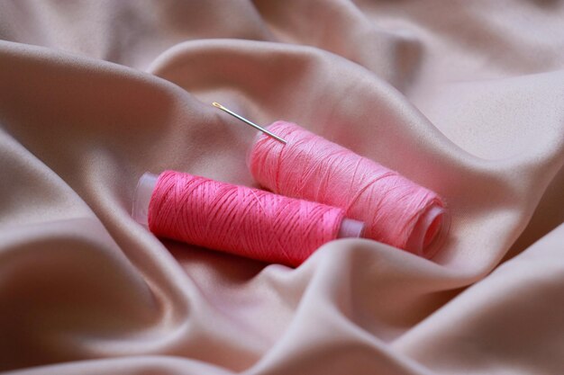 close up of a pink sewing coil thread on silk textile