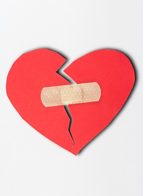 Close up of plaster and paper broken heart on white background.