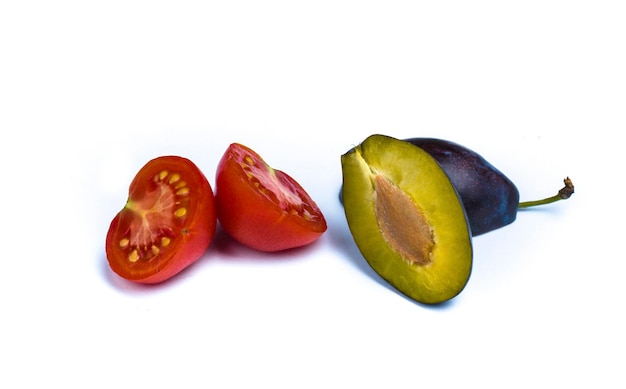 Photo close-up of plum with tomato slices on white background