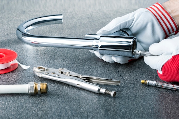 Close-up of plumber hands with faucet on grey title background.